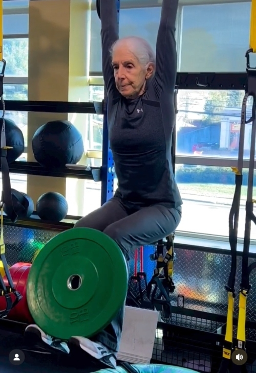 勞倫吊在單槓上，屈膝上舉並且負重10磅。