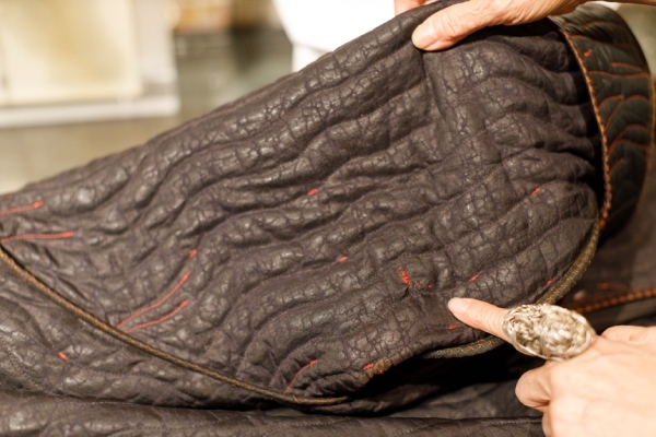 縫補黑色鋪棉大衣時，洪麗芬使用布料上原有的胭脂紅絲線。
