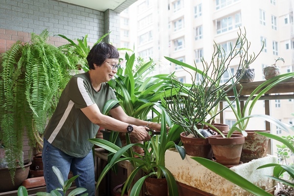 照顧前陽台上的綠植，讓劉綺文感受到生命的變化與可貴。她背後的蕨類，已養了21年！