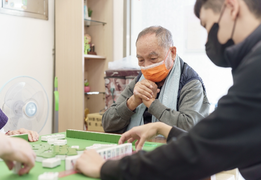長輩正聚精會神地與大學生一起打麻將。