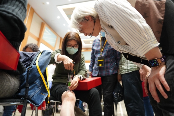 除在台上講解，沈邑穎亦下台指導《50+》學員。圖為拔罐實作。