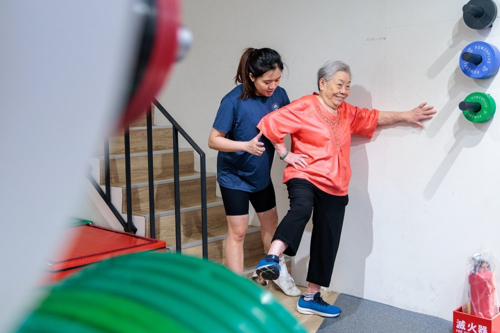上課時，教練林亞儒細心指導91歲的鄭陳金梅做暖身運動。