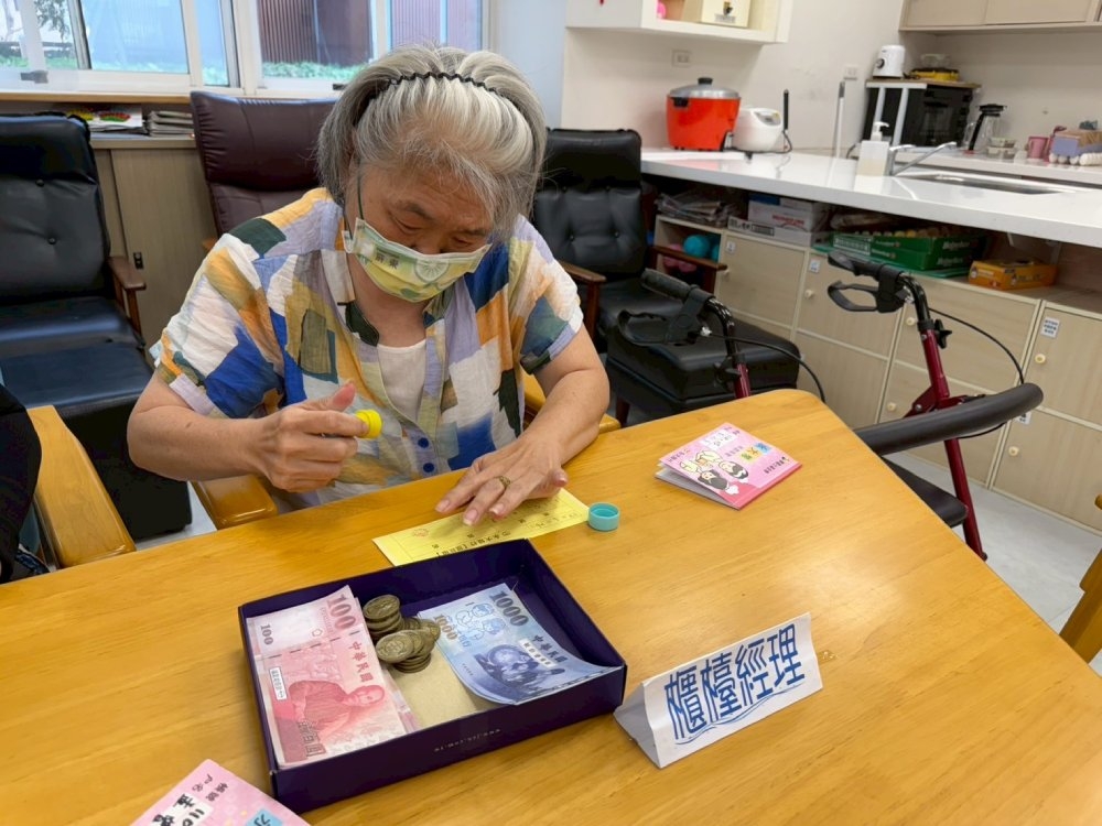 擔任櫃台經理的長輩要仔細核對提款單和存摺的數字，然後取出相應數字的永大幣給前來提錢的人。（圖片來源：畢嘉士基金會）
