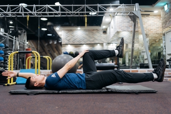 步驟三：右手碰觸左腳膝蓋，同時左手向後伸直，右腳同時往前延伸不落地，保持1~2秒後慢慢回到起始位置。（圖片來源：影巷26號攝）