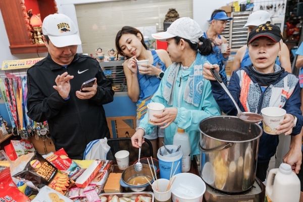 週二練跑結束後，南港慢跑社成員聚集在總部吃吃喝喝。有朋友一起享受美食，小點心也變得格外可口。（圖片來源：孫百毅攝）