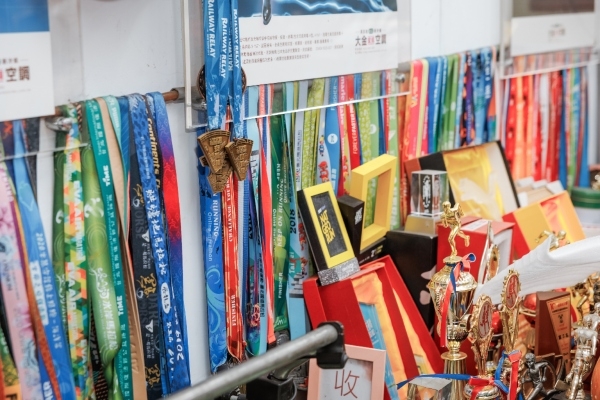南港慢跑團經常組隊參加台灣各地慢跑賽事，歷年來收集到的獎牌，成了總部的一道風景。（圖片來源：孫百毅攝）
