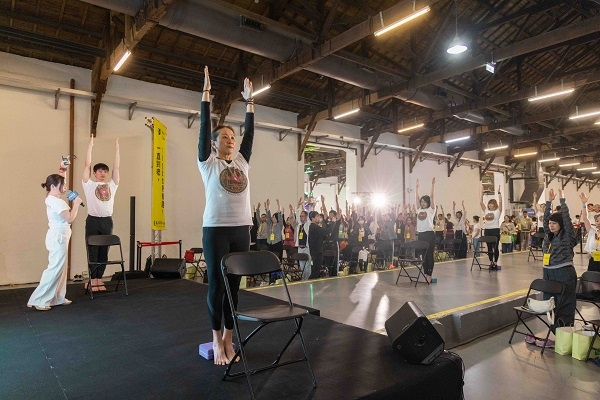 正位瑜珈講師鄧燕英講解，搭配助教示範如何巧用一塊瑜珈磚，讓參加者在家也能輕鬆練習，找回身體的挺拔與平衡。（圖片來源：易志強攝影工作室） 