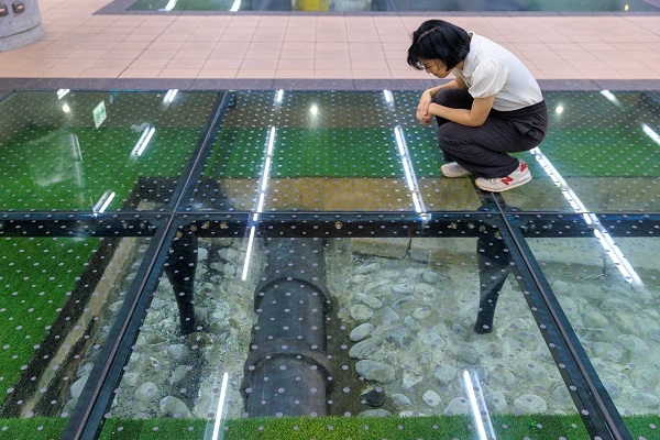 捷運局在興建北門站進行考古挖掘時，選擇將清代的鵝卵石基礎、條石排水溝，以及日治時期穿過其中的地下水管原地保存，讓民眾能一眼看見台北百年間不同時代公共工程交錯疊加的歷史軌跡。（圖片來源：葉琳喬攝） 